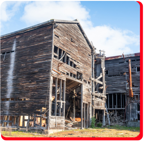 A severely deteriorated wooden barn near Toronto stands with missing walls and exposed beams, illustrating the urgent need for structural restoration and preservation services.