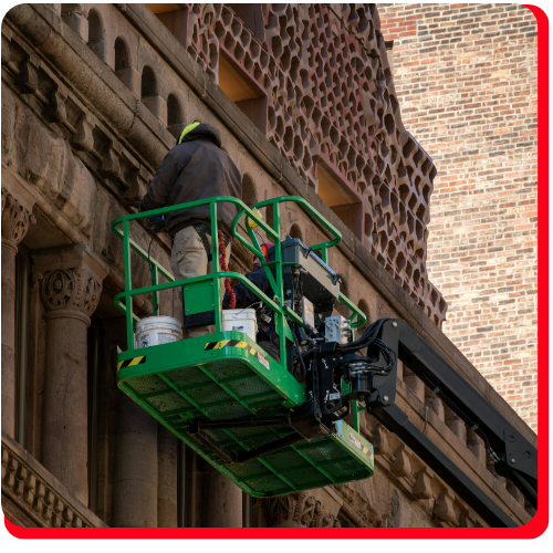 echnician on hydraulic lift performing detailed brick and stone restoration on a historic Toronto building façade.