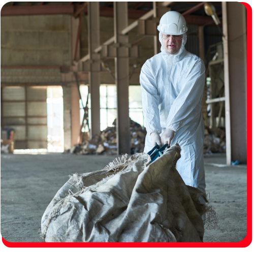 Worker in full protective gear hauling contaminated material during a chemical spill cleanup operation inside an industrial facility in Toronto.