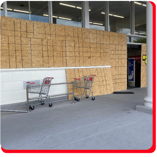 Boarded-up storefront in Toronto, Ontario, with plywood covering the entrance and windows, indicating recent commercial property damage, with shopping carts positioned outside.