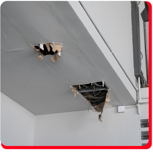 Damaged commercial ceiling in Toronto, Ontario, with two large holes exposing wiring and structural materials, requiring professional damage assessment and restoration services.