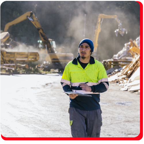 Construction inspector in Toronto, Ontario, wearing a high-visibility jacket and beanie, holding a clipboard while assessing commercial property damage at an active demolition site with heavy machinery in the background.