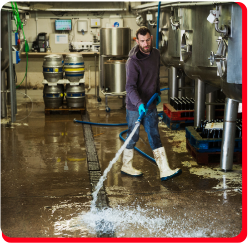 Technician using industrial equipment to extract standing water from a flooded commercial facility floor.