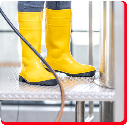 Close-up of a technician wearing yellow waterproof boots on a wet metal surface during a commercial water extraction job.
