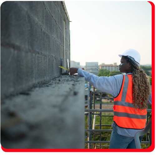 Female construction worker in Toronto, Ontario, Canada wearing a safety vest and hard hat, measuring a concrete wall as part of a building restoration and masonry repair project.