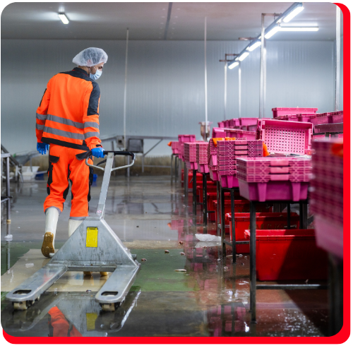 Worker in protective gear navigating a wet industrial facility with standing water during an emergency commercial water extraction operation.