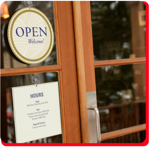 Glass door of a commercial business with open signage and visible business hours, emphasizing the importance of stormwater management to protect entrances from flooding and water damage.