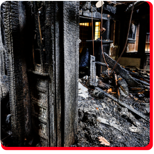 A severely fire-damaged commercial interior with blackened, charred wood framing and extensive debris covering the floor, indicating large loss restoration needs in Toronto, Ontario, Canada.