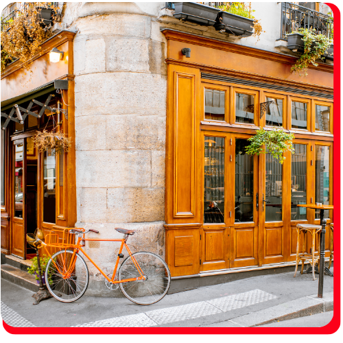 Charming heritage building restoration in Toronto featuring a preserved stone facade, wrought-iron balcony, classic awning, and outdoor café seating with potted greenery.