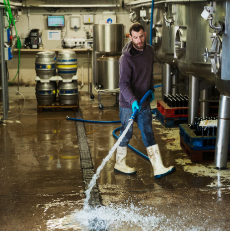 Technician using industrial equipment to extract standing water from a flooded commercial facility floor.