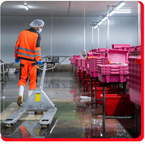 Worker in protective gear navigating a wet industrial facility with standing water during an emergency commercial water extraction operation.