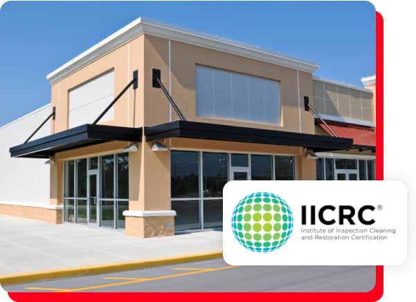 A modern commercial building with large windows displaying the IICRC logo and text reading Institute of Inspection Cleaning and Restoration Certification, highlighting services such as commercial restoration, fire damage restoration, water damage restoration, commercial fire restoration, and commercial water damage restoration.