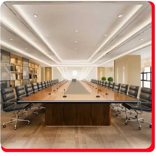 A spacious, modern conference room featuring a long rectangular table, black swivel chairs, ceiling lights, and shelves along the left wall. The well-lit and empty room includes plants and microphones on the table—showcasing a professional space maintained with expert commercial restoration services such as fire damage restoration and water damage restoration. This ideal meeting environment highlights the results of thorough commercial fire restoration and commercial water damage restoration efforts.
