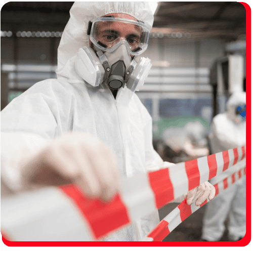 A worker in protective gear and a respirator mask holds red-and-white caution tape, cordoning off a hazardous zone during commercial fire restoration or commercial water damage restoration. Another technician in similar safety attire appears in the background, illustrating the careful procedures involved in commercial restoration for fire or water damage.
