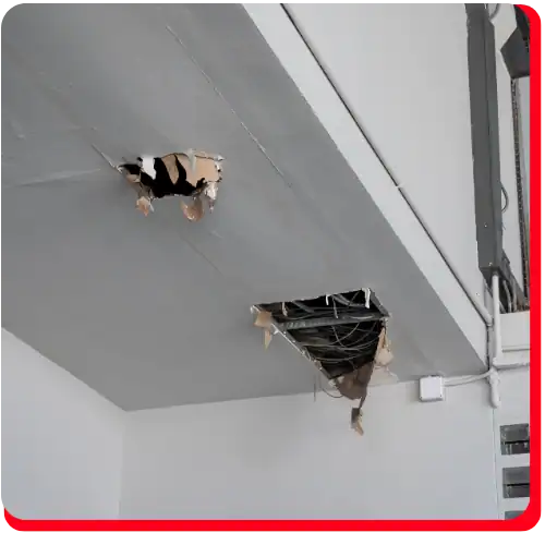 A white ceiling in need of commercial restoration, featuring two large holes with exposed wires and broken drywall, indicating significant fire damage restoration or water damage restoration may be required for this commercial property.