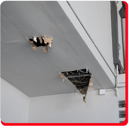 Damaged commercial ceiling in Toronto, Ontario, with two large holes exposing wiring and structural materials, requiring professional damage assessment and restoration services.