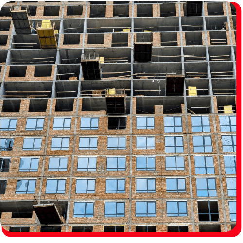 Unfinished high-rise building displaying exposed concrete floors and walls on the upper levels, with completed brickwork and glass windows on lower floors. Visible construction materials emphasize the importance of commercial water damage restoration and commercial fire restoration solutions during construction, as well as broader needs for fire damage restoration and water damage restoration services in commercial restoration projects.