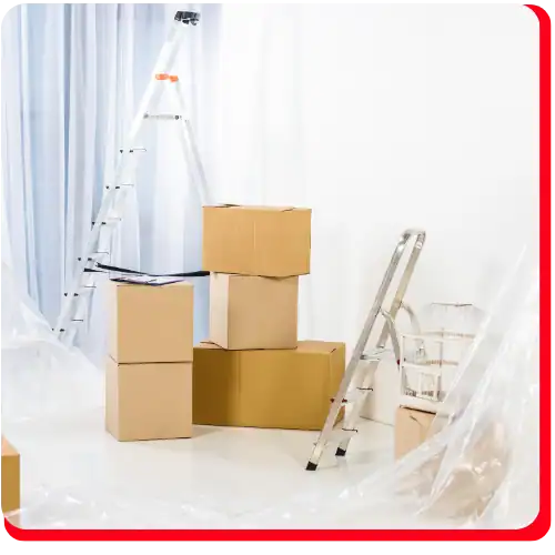 Five cardboard boxes are stacked in a white room with two ladders and clear plastic sheets hanging nearby, creating a scene commonly found during commercial restoration projects such as fire damage restoration or water damage restoration. The setup indicates ongoing commercial fire restoration or commercial water damage restoration activities.