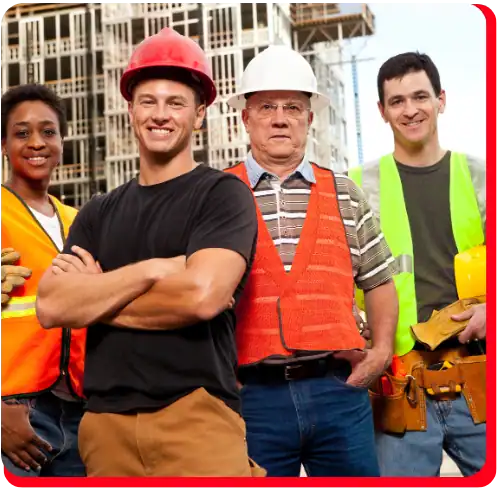 Four construction workers wearing safety vests and helmets stand smiling at a commercial restoration site, with buildings in the background, representing professionals specializing in fire damage restoration, water damage restoration, commercial fire restoration, and commercial water damage restoration.