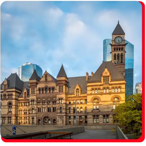 A historic stone building with a clock tower stands before modern glass skyscrapers under a blue sky, highlighting the essential role of commercial water damage restoration and commercial fire restoration in protecting architectural landmarks from water damage and fire amid rapid urban development.